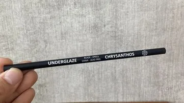 Lápiz cerámico negro Chrysanthos Underglaze sostenido en la mano